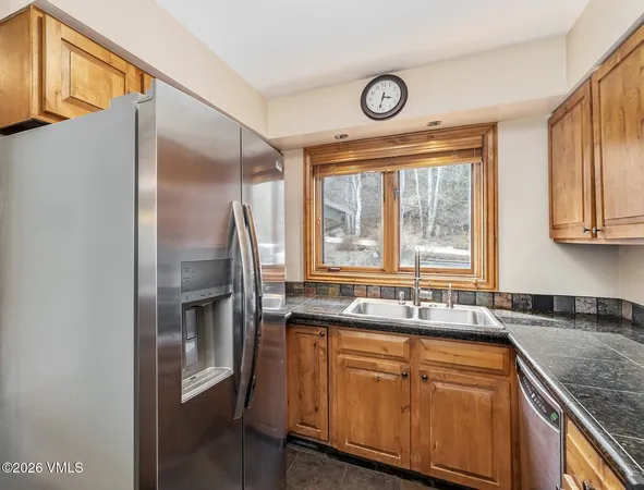 a kitchen with stainless steel appliances granite countertop a sink and a refrigerator