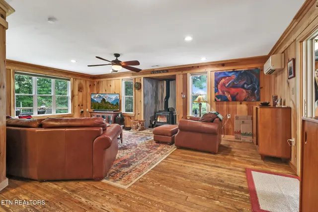 a living room with furniture ceiling fan and a large window