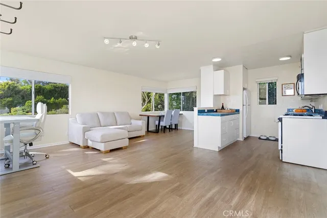a living room with furniture and kitchen view with wooden floor