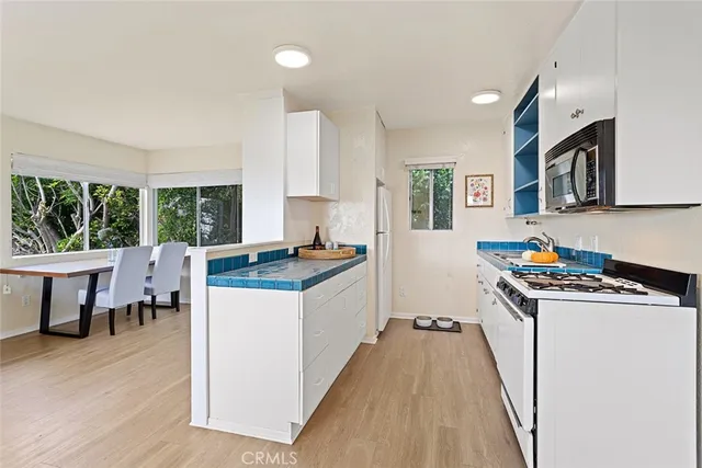 a kitchen with stainless steel appliances granite countertop a stove top oven a sink a dining table and chairs