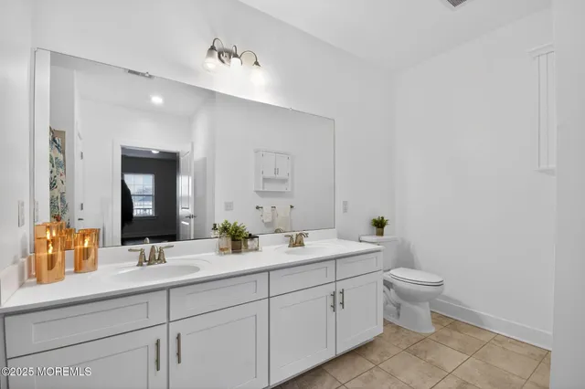 a spacious bathroom with a double vanity sink toilet and mirror