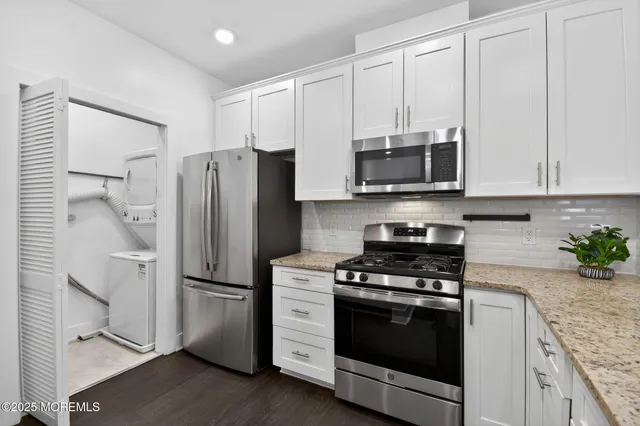 a kitchen with stainless steel appliances white cabinets white stove a microwave and a refrigerator