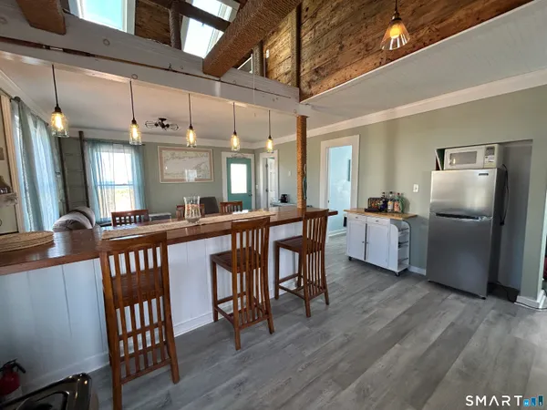 a kitchen with stainless steel appliances kitchen island granite countertop a table chairs and a refrigerator