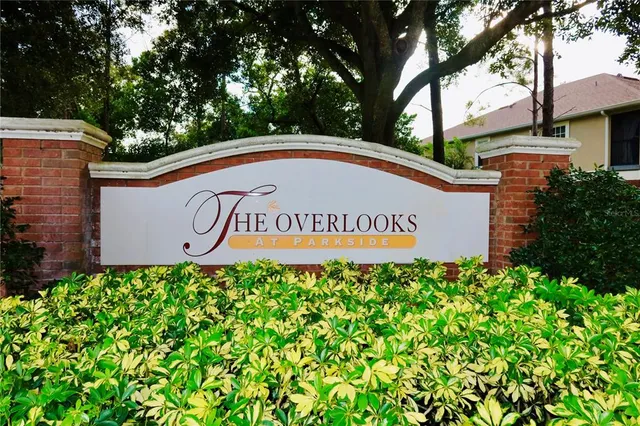 a sign of golf club on a wall under a tree