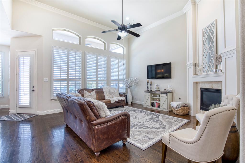 1552 Saddle Tree Road Frisco, TX 75036 - Photo 10 of 40 Beautiful, Open Family room featuring wood floors, plantation shutters with multiple windows, Crown molding, fireplace and ceiling fan.