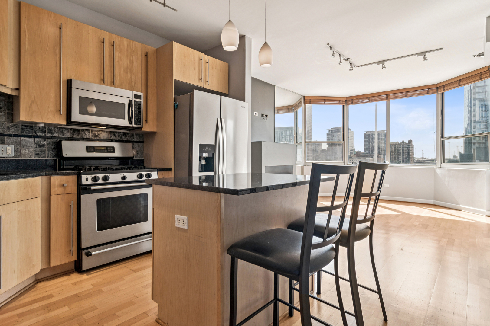720 West Randolph Street, Unit 502 Chicago, IL 60661 - Photo 4 of 22 a kitchen with stainless steel appliances kitchen island granite countertop a stove a refrigerator a dining table and chairs with wooden floor
