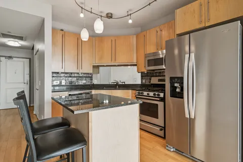a kitchen with stainless steel appliances granite countertop a stove refrigerator and a sink