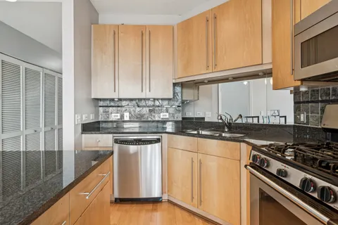 a kitchen with stainless steel appliances granite countertop a stove a sink and white cabinets