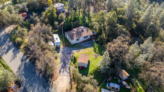 an aerial view of house with green field and mountains