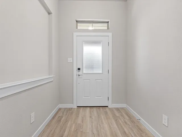 a view of an empty room with wooden floor and a ceiling fan