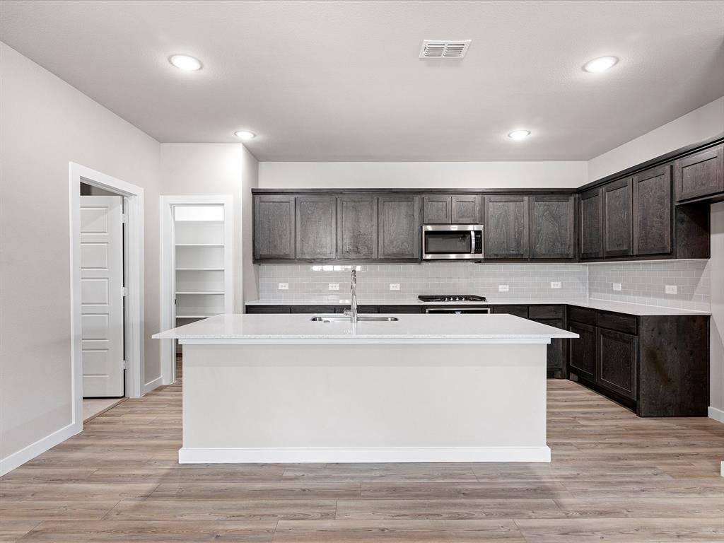 643 Medinah Road Red Oak, TX 75154 - Photo 8 of 28 a large kitchen with stainless steel appliances granite countertop a stove a sink dishwasher a refrigerator and a microwave oven with wooden floor