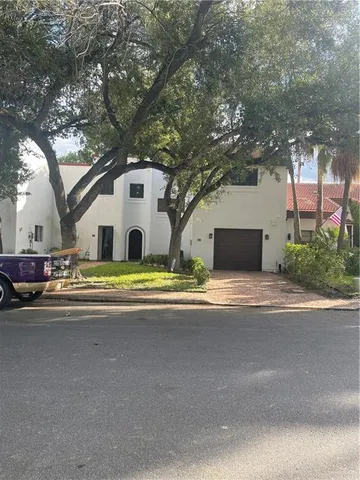 a view of a white house with a large tree