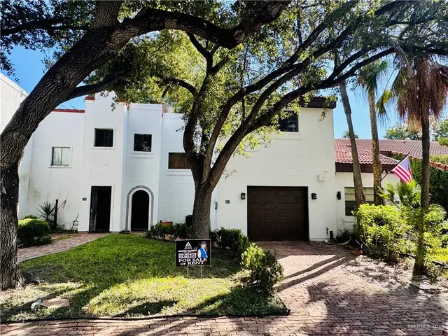 a view of a white house with a large tree and a yard