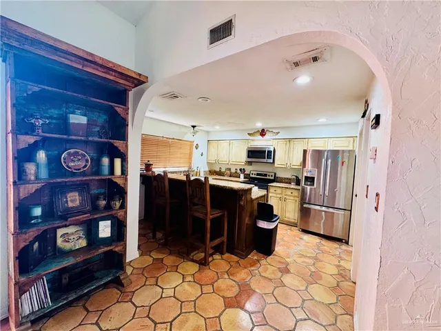 a kitchen with stainless steel appliances kitchen island granite countertop a refrigerator and a sink