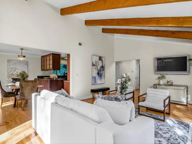 a view of a dining room with furniture a kitchen and chandelier