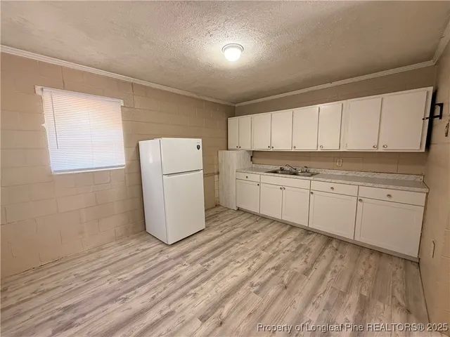a kitchen with a sink a refrigerator and white cabinets