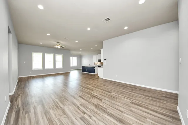 a view of empty room with wooden floor and windows