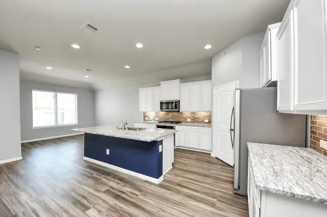 a kitchen with kitchen island sink refrigerator and cabinets