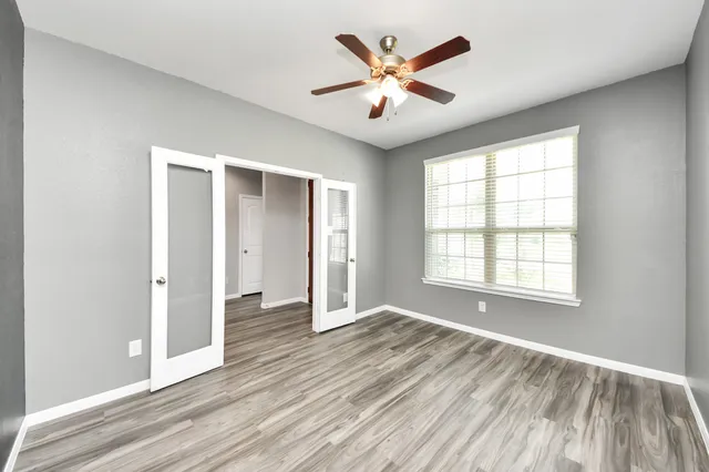 an empty room with wooden floor and windows