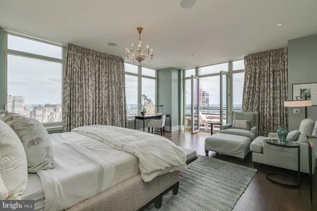 a spacious bedroom with double bed windows and a chandelier