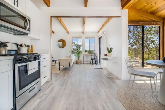 a kitchen with stainless steel appliances a stove a table and chairs with wooden floor