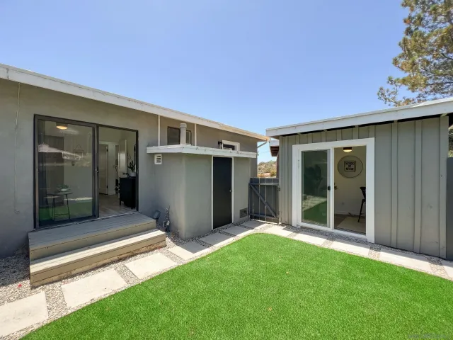 a view of a white house with a large tree