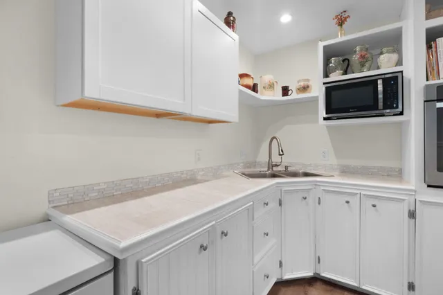 a kitchen with white cabinets a sink and wooden floor