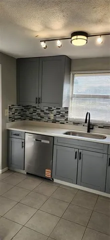 a sink with a granite countertop window and white cabinets