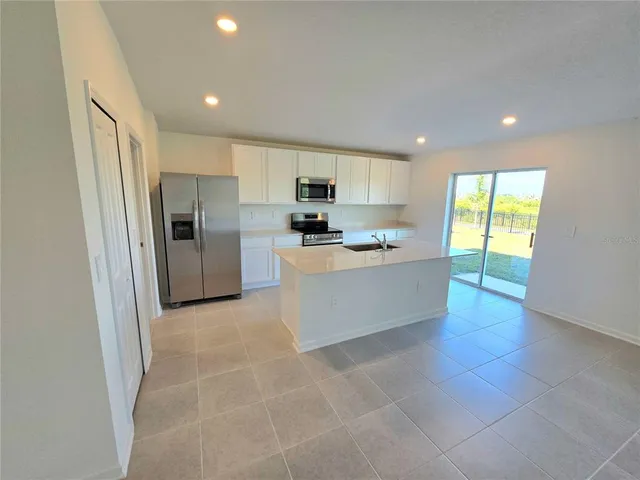 a large kitchen with stainless steel appliances granite countertop a stove a sink and a refrigerator