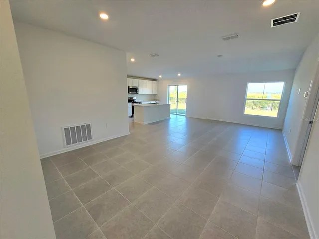a view of empty room with windows and kitchen view