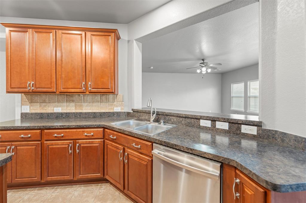 500 Braewick Drive Fort Worth, TX 76131 - Photo 11 of 35 a kitchen with granite countertop a sink stainless steel appliances white cabinets and a window