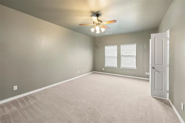 an empty room with windows and chandelier fan