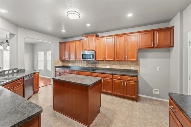 a kitchen with stainless steel appliances granite countertop wooden cabinets a sink and a large window