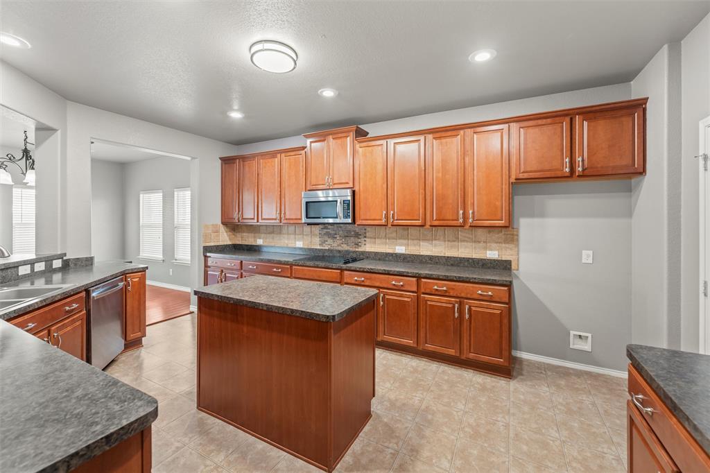 500 Braewick Drive Fort Worth, TX 76131 - Photo 9 of 35 a kitchen with stainless steel appliances granite countertop wooden cabinets a sink and a large window