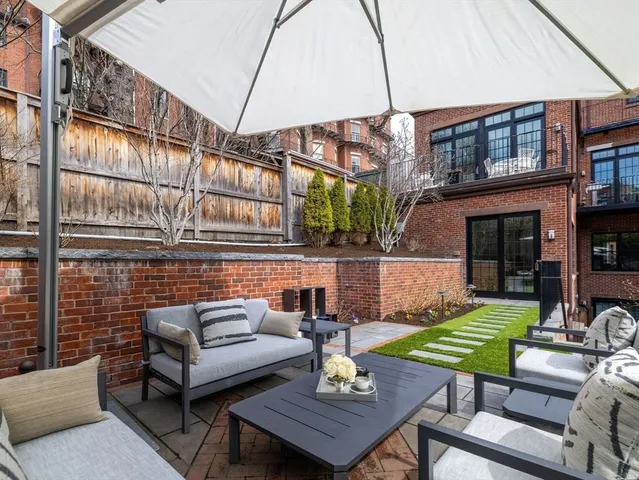 a view of a patio with couches table and chairs under an umbrella