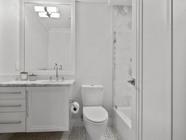 a bathroom with a granite countertop toilet a sink and a mirror