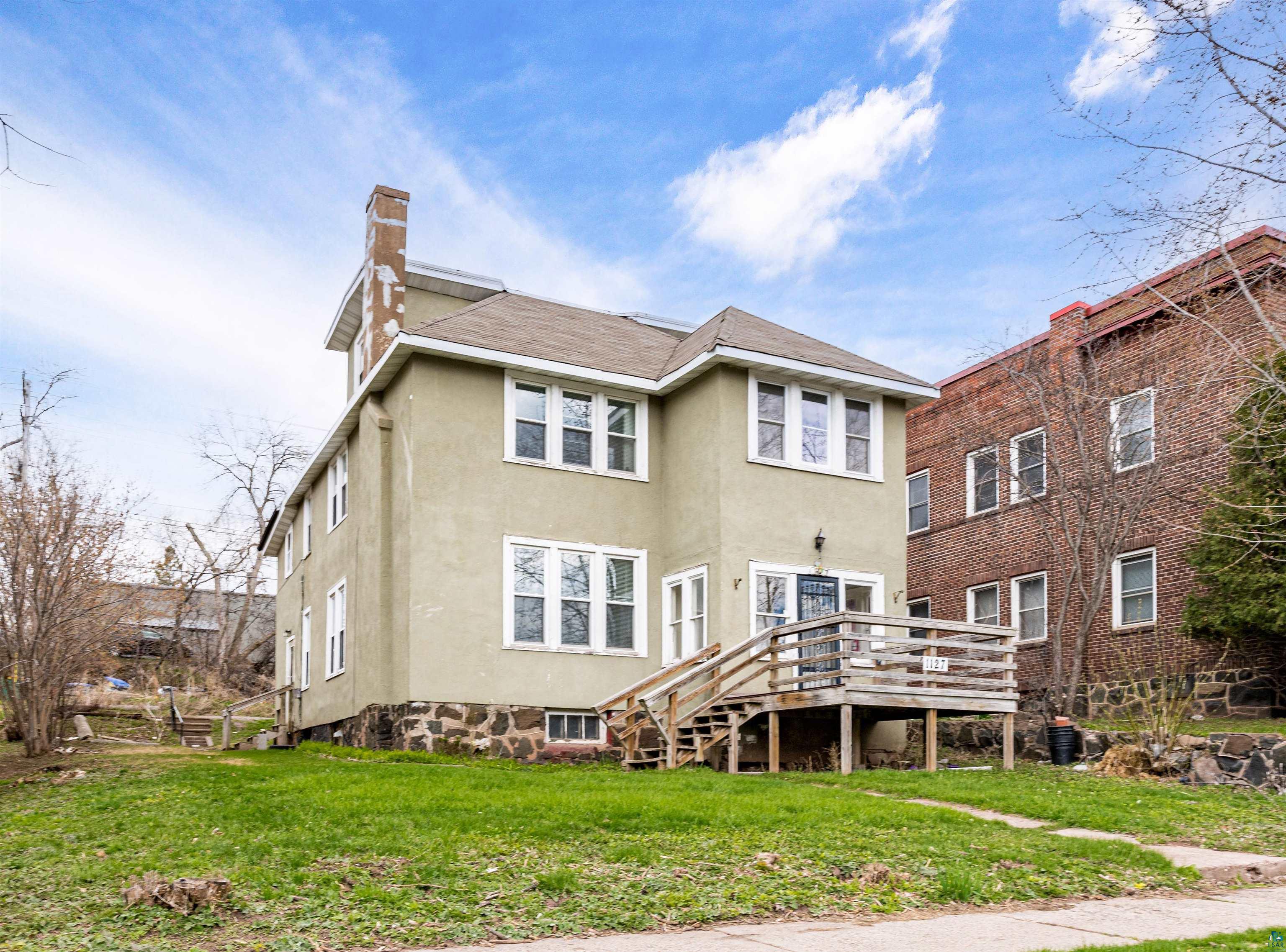 1127 East 3rd Street Duluth, MN 55805 - Photo 1 of 28 Rear exterior featuring a deck with railing, a stucco finish, and a stone foundation