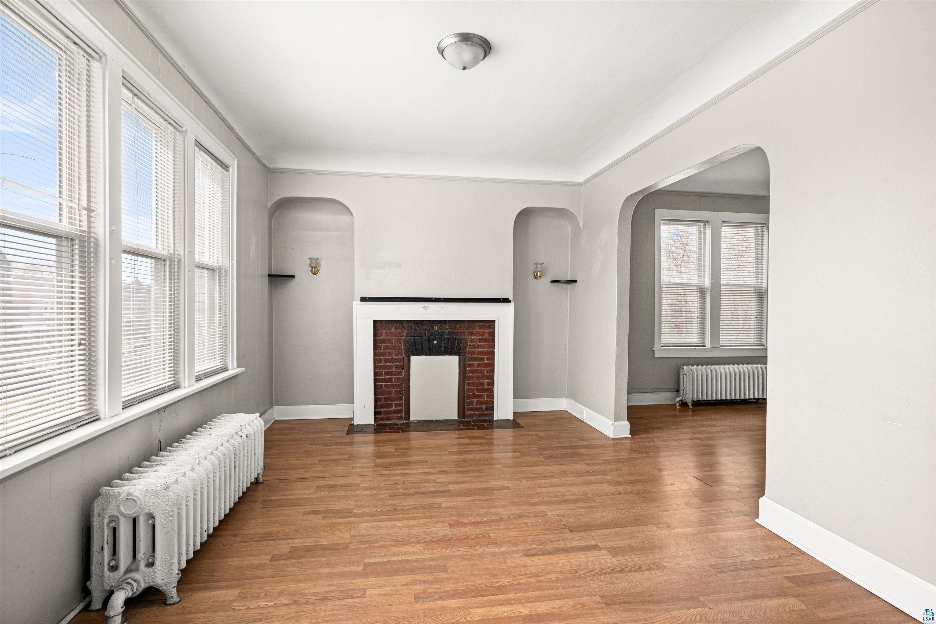 1127 East 3rd Street Duluth, MN 55805 - Photo 2 of 28 Spacious room featuring wood-finish flooring and a brick fireplace