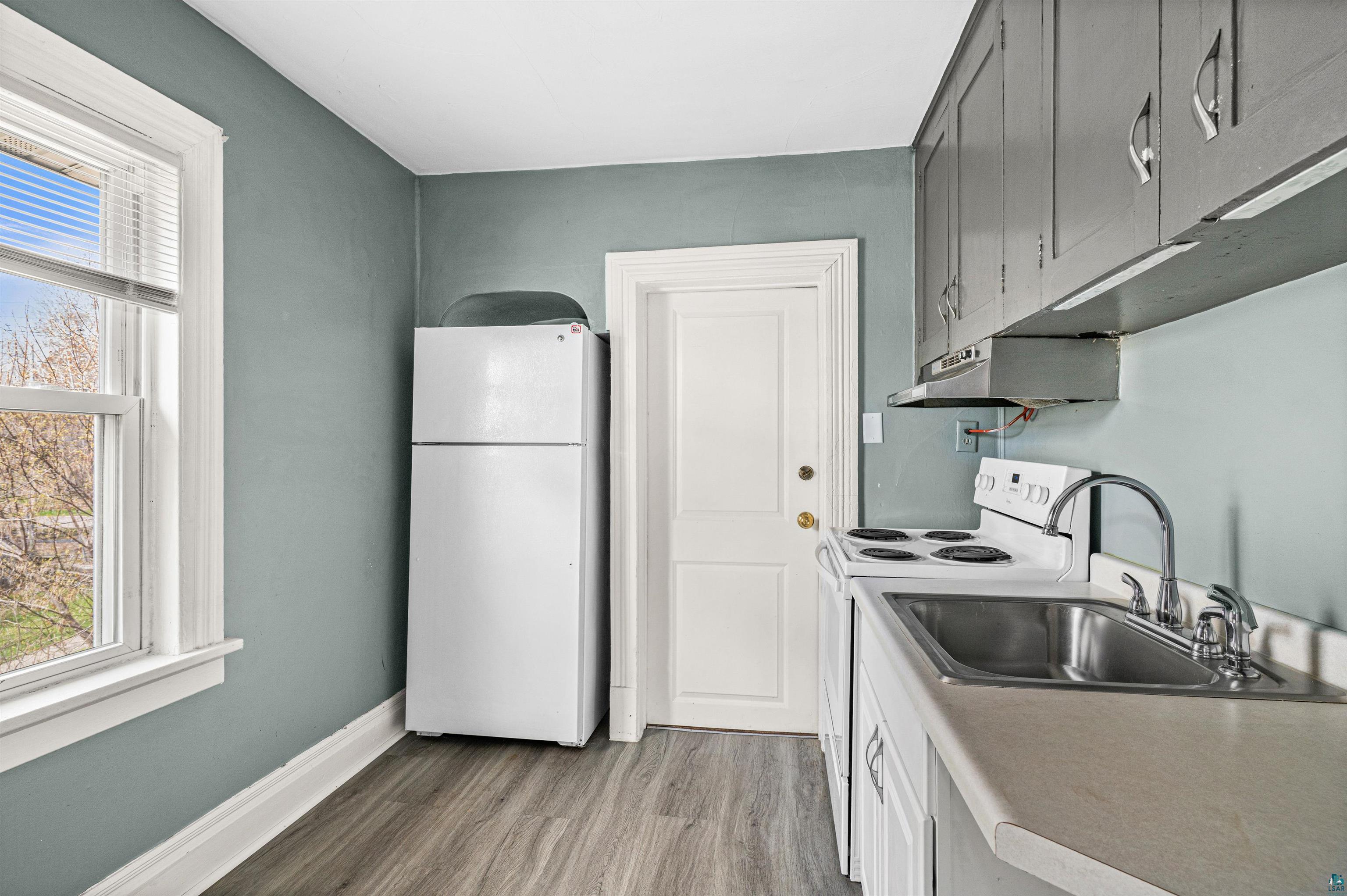 1127 East 3rd Street Duluth, MN 55805 - Photo 23 of 28 Kitchen featuring wood-finish flooring, a white refrigerator, a white range, a stainless steel sink, and gray upper cabinetry