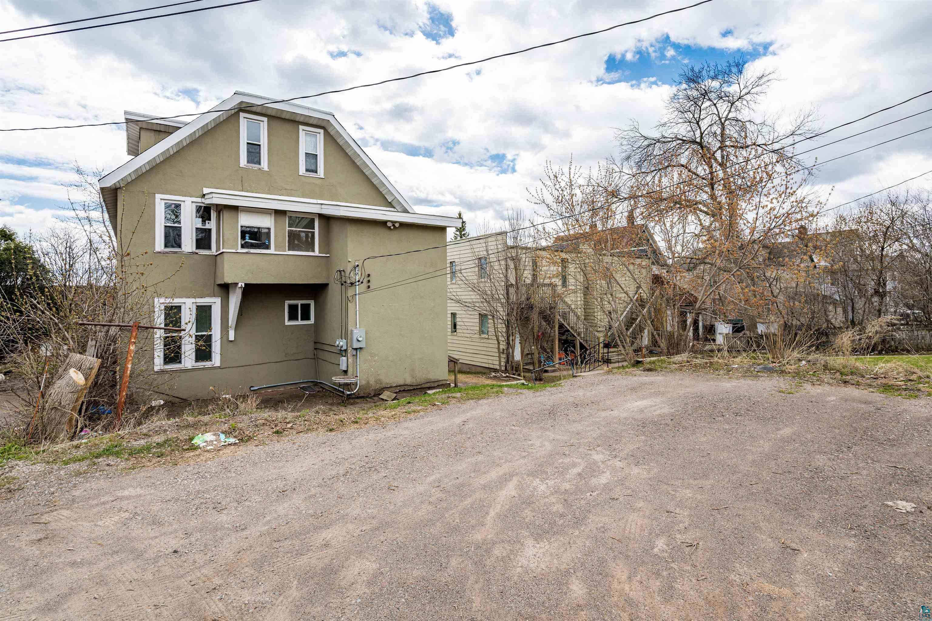1127 East 3rd Street Duluth, MN 55805 - Photo 25 of 28 Green stucco exterior with white trim windows and a gambrel roofline