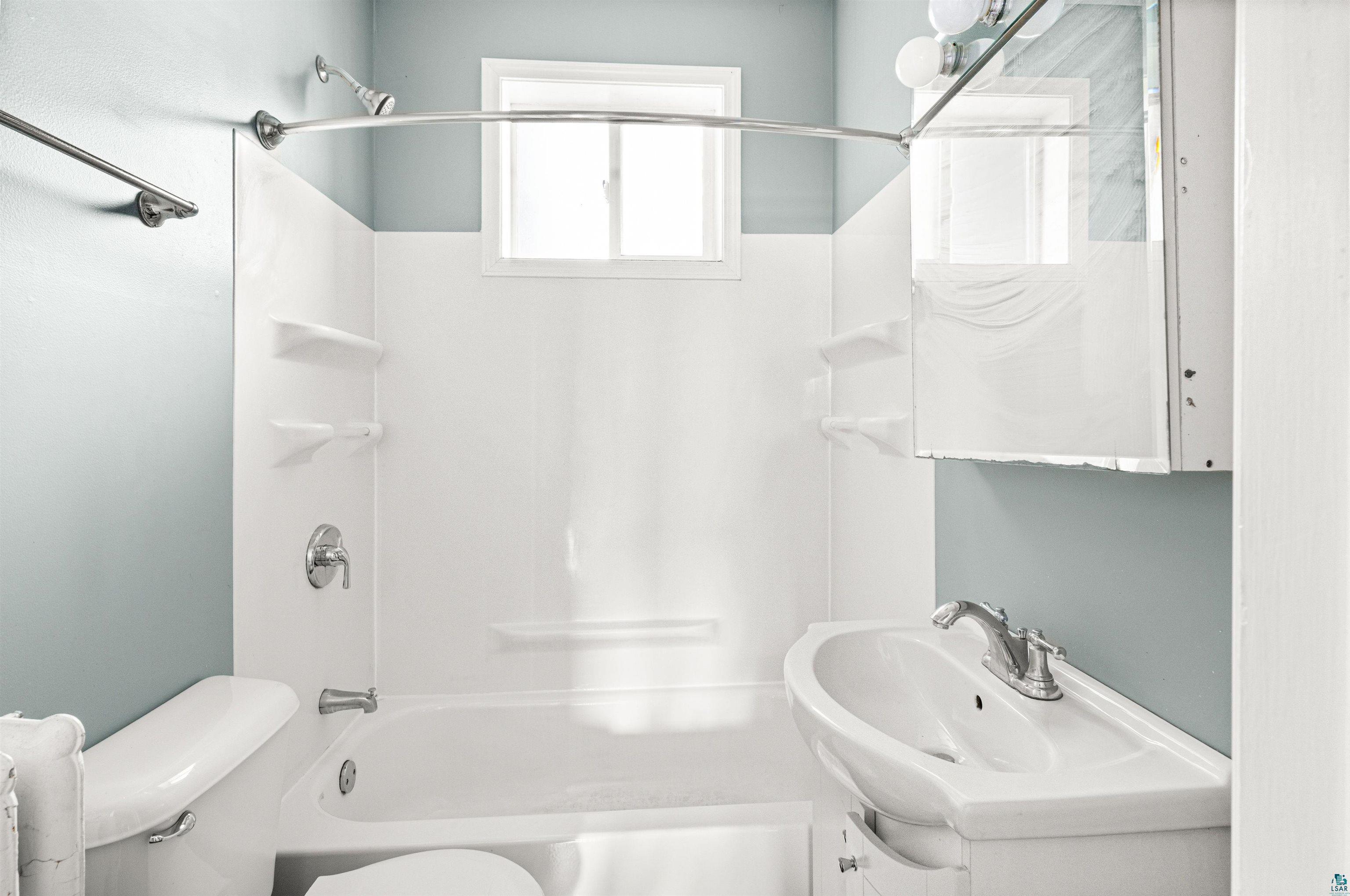 1127 East 3rd Street Duluth, MN 55805 - Photo 9 of 28 Bathroom featuring a white bathtub, toilet, and pedestal sink