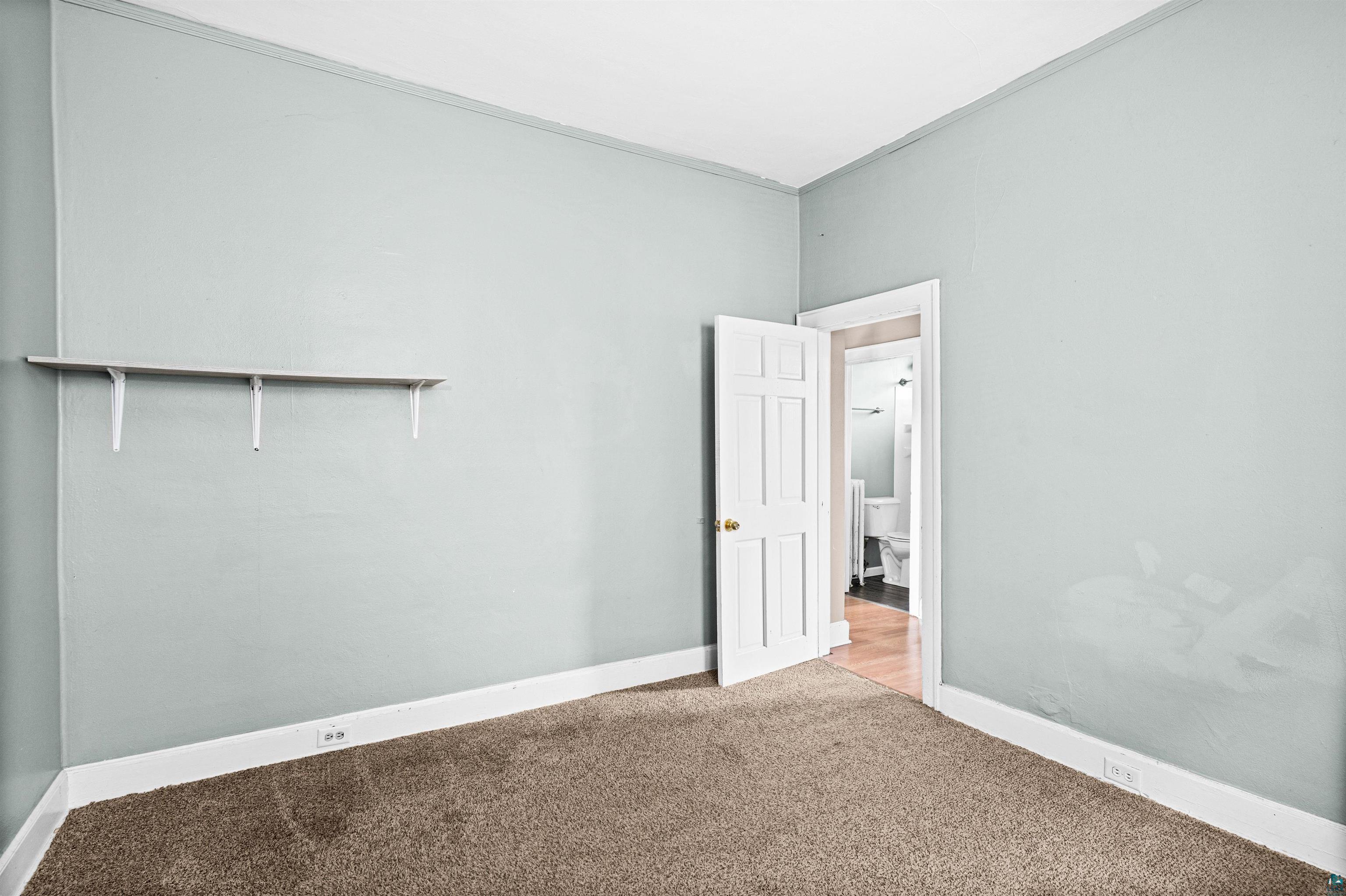 1127 East 3rd Street Duluth, MN 55805 - Photo 10 of 28 Room with light blue wall paint, wall-to-wall carpeting, white baseboards, and a white interior door