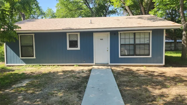 a backyard of house with large window and wooden fence