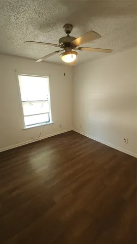 an empty room with a chandelier fan and windows