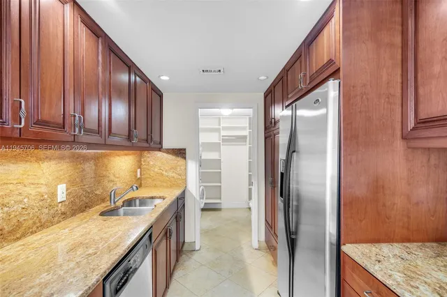 a kitchen with stainless steel appliances granite countertop a refrigerator a stove and a sink