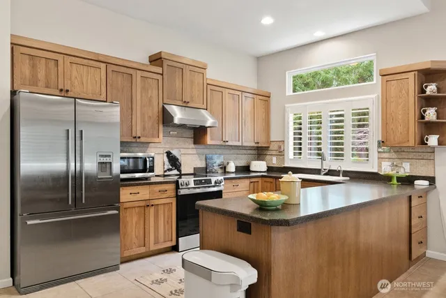 a kitchen with stainless steel appliances granite countertop a sink stove refrigerator and window