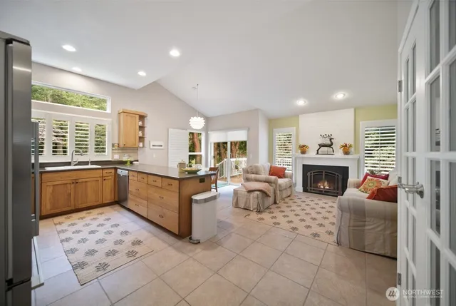 a large living room with stainless steel appliances kitchen island granite countertop a large window and a fireplace