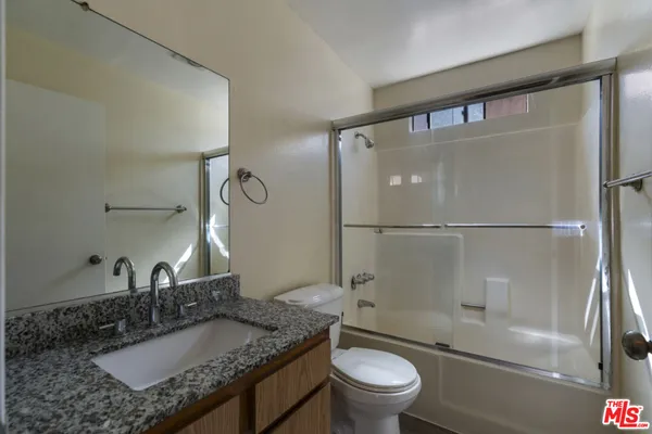 a bathroom with a granite countertop sink toilet and shower