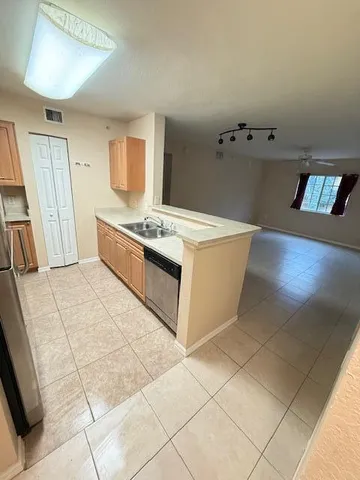 a view of an empty room with window and chandelier fan