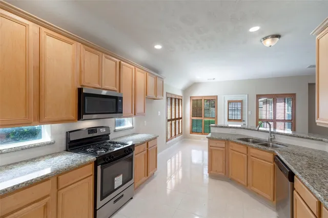 a kitchen with stainless steel appliances granite countertop a sink a stove and cabinets